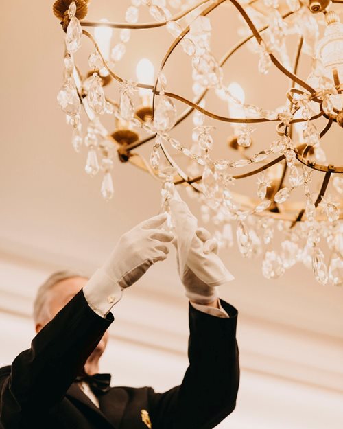 An employee at Hotel Bristol polishing a large chandelier